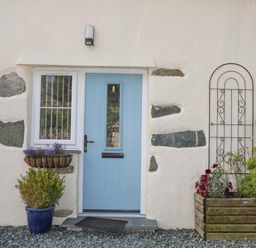 A blue door with a window and plants in pots outside at Ffynnon Bach in Deiniolen