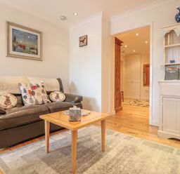 A living room with a leather sofa cushions a wooden coffee table a white cabinet and a painting on the wall at Church Road Annexe in Cinderford
