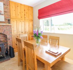 A dining area with wooden table and chairs a brick fireplace and built in wooden cabinets at Sea View Hideaway in Lahinch County Clare