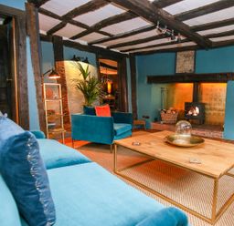 A living room with blue sofas a wooden coffee table a fireplace and exposed wooden beams at 3 Masons Court in Stratford-Upon-Avon