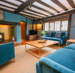 A living room with blue sofas a wooden coffee table and a fireplace at 3 Masons Court in Stratford-Upon-Avon