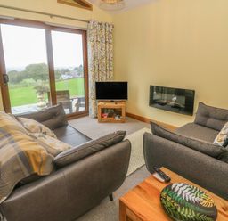 A living room with two sofas a television and sliding glass doors leading to a patio at Nicky Nook Lodge in Scorton