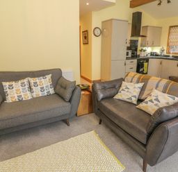 A living room with two sofas and a kitchen area at Nicky Nook Lodge in Scorton