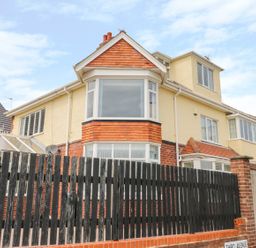 A two-story house with bay windows a black wooden fence and a brick wall at The Gansey Girl in Bridlington