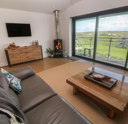 A living room with a sofa and a fireplace at Sandpiper in Perranporth