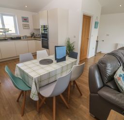 A kitchen with a dining table and chairs at Sandpiper in Perranporth