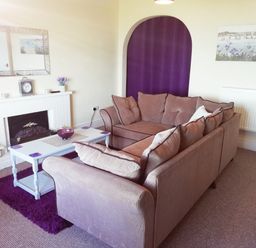 A living room with two sofas a white coffee table and a fireplace with a mirror above at Llys Madoc The Top Flat in Penmaenmawr