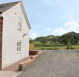 Exterior of a white brick house with windows and a gravel driveway overlooking green hills and fields at Conquer Hall in Hendomen near Montgomery