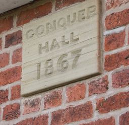 A brick wall with a stone plaque reading Conquer Hall 1867 at Conquer Hall in Hendomen near Montgomery