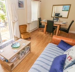 A living room with a sofa and coffee table next to a dining table with chairs at 2 Primrose Cottage Saundersfoot