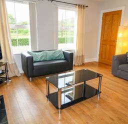 A living room with two sofas a glass coffee table a television and a floor lamp at Croghan in Portsalon