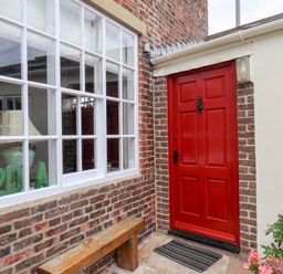 An outdoor area with a red front door and a bench at 20A St Hilda's in Whitby