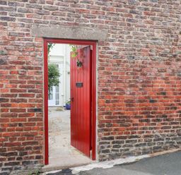 A red door opening to a courtyard at 20A St Hilda's in Whitby