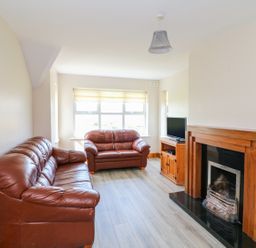 A living room with two brown leather sofas a wooden fireplace and a TV on a wooden cabinet at Doornogue in Churchtown near Fethard-on-Sea