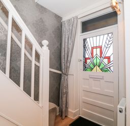 A staircase next to a front door with stained glass window and a curtain at Yr Adfa The Retreat in Blaenau Ffestiniog