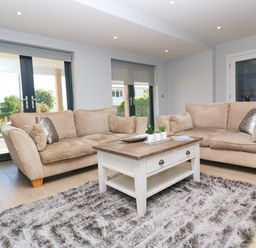 A living room with two beige sofas a wooden coffee table and a gray rug at Driftwood Haven in Carbis Bay
