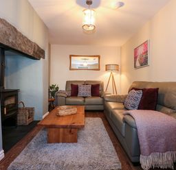 A living room with two sofas a wooden coffee table a rug a floor lamp and a fireplace at Yr Hen Dy Capel in Blaenau Ffestiniog