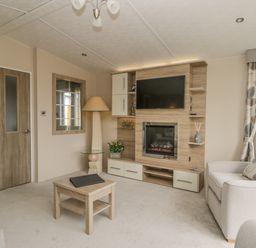 A living room with a wall-mounted TV and electric fireplace a wooden coffee table a floor lamp a large mirror and a sofa at The Sequoia in Cloughton