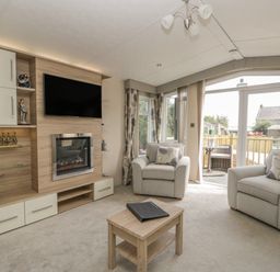 A living room with two armchairs a coffee table a wall-mounted television and a fireplace at The Sequoia in Cloughton