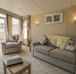 A living room with a beige sofa and armchair with cushions a wooden coffee table and framed artwork at The Sequoia in Cloughton