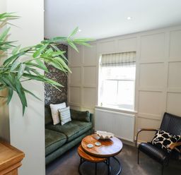 A sitting area with a green sofa and black chair around a wooden coffee table under a window at Gavel Cottage in Whitby