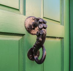 A green door with a decorative metal knocker at Cobbles House, Whitby