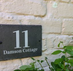 A house number and name plaque on a wall at Damson Cottage in Whitby