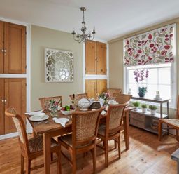 A dining room with a wooden table set for six people and wooden chairs at Harbour House in Whitby