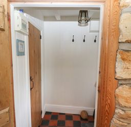 A small entryway with wooden door and three hooks on the wall at The Cottage in Sandsend