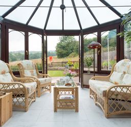 A conservatory with wicker furniture and floral cushions overlooking a garden at Seawinds in Robin Hood'S Bay