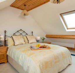 A bedroom with a double bed a skylight window wooden bedside tables with lamps and flower vases at Seawinds in Robin Hood S Bay