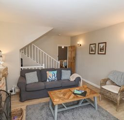A living room with a gray sofa and wicker chair near a wooden coffee table and fireplace at Rooftops Cottage in Whitby