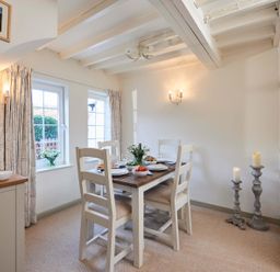 A dining room with a wooden dining table set with plates and candles at Rigg Cottage in Sandsend