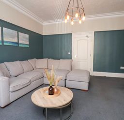 A living room with a grey sectional sofa a round wooden coffee table and blue walls at Church View in Whitby