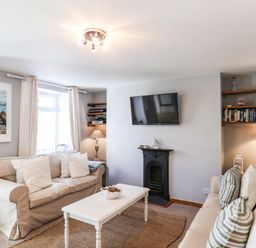 A living room with two sofas a wall-mounted TV and bookshelves at Albany Cottage in Whitby