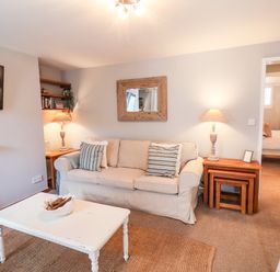 A living room with a beige sofa two side tables with lamps a white coffee table and a wall-mounted tv at Albany Cottage in Whitby