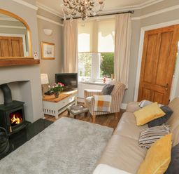 A living room with a fireplace sofa armchair television and a window at Arden House Whitby