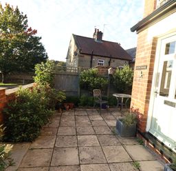 A small paved front garden area with plants chairs and a table outside a house at Arden House in Whitby