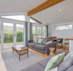 A living room with two sofas coffee table dining table and large windows at 6 Valley View in Lanreath
