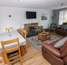 A living room with a dining area and sofa at Ty'r Winllan in Newport, Pembrokeshire