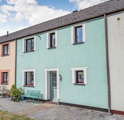 A row of terraced houses with benches and potted plants outside at Granary Cottage in Pembroke