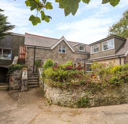 An exterior view of a stone house with greenery and plants around it at Gorwel in Moelfre