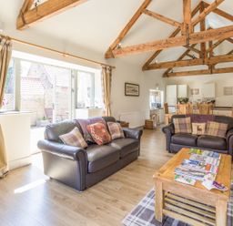 A living room with two leather sofas a wooden coffee table and exposed wooden beams at Sawmill Cottage in Belford near Bamburgh