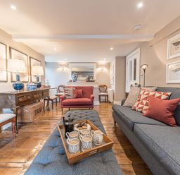 A living room with a blue sofa and red armchair wooden furniture and bird artwork at Prospect House in Ambleside