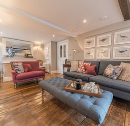 A living room with a gray sofa a red armchair wooden floor and framed bird pictures on the wall at Prospect House in Ambleside