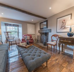A living room with wooden floor a gray sofa a red armchair a wooden chair a fireplace and a wooden table with a lamp at Prospect House in Ambleside