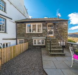 An outdoor patio with stone stairs leading to a door and a small table with chairs at Prospect Cottage Loft in Ambleside