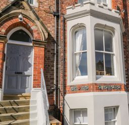 An entrance door with steps and a bay window on a brick building at 1 Church Square in Whitby