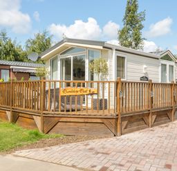 A single story mobile home with wooden deck and outdoor seating at Ramblers Rest in Felton