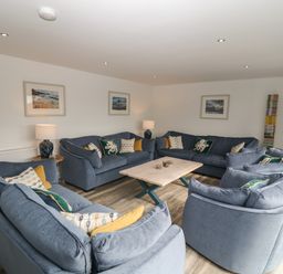 A sitting room with blue sofas and a wooden coffee table at Argraig in Llanbedrog